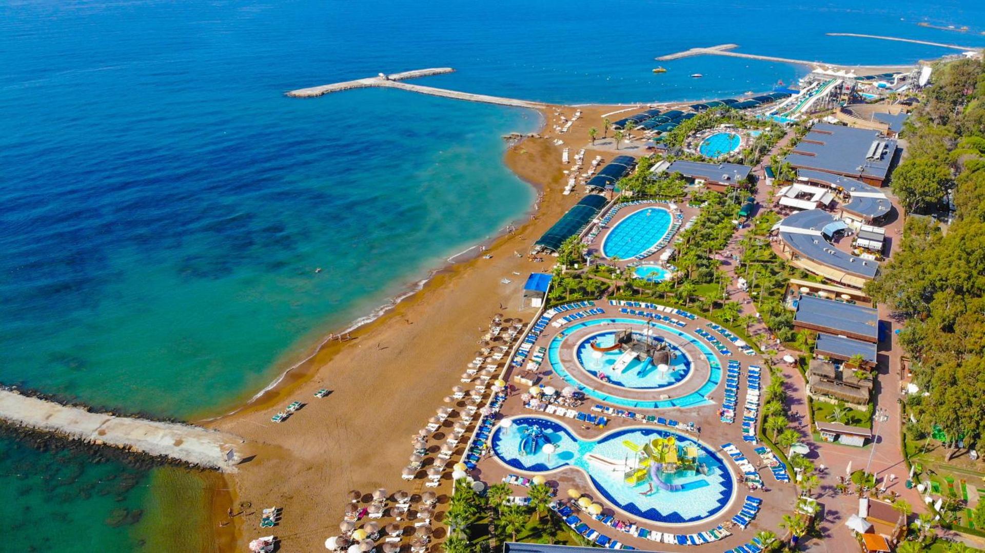 Eftalia Village privātā pludmale un Eftalia Island akvaparks pie Vidusjūras — bērnu baseini ar atrakcijām un saulessargi smilšu pludmalē