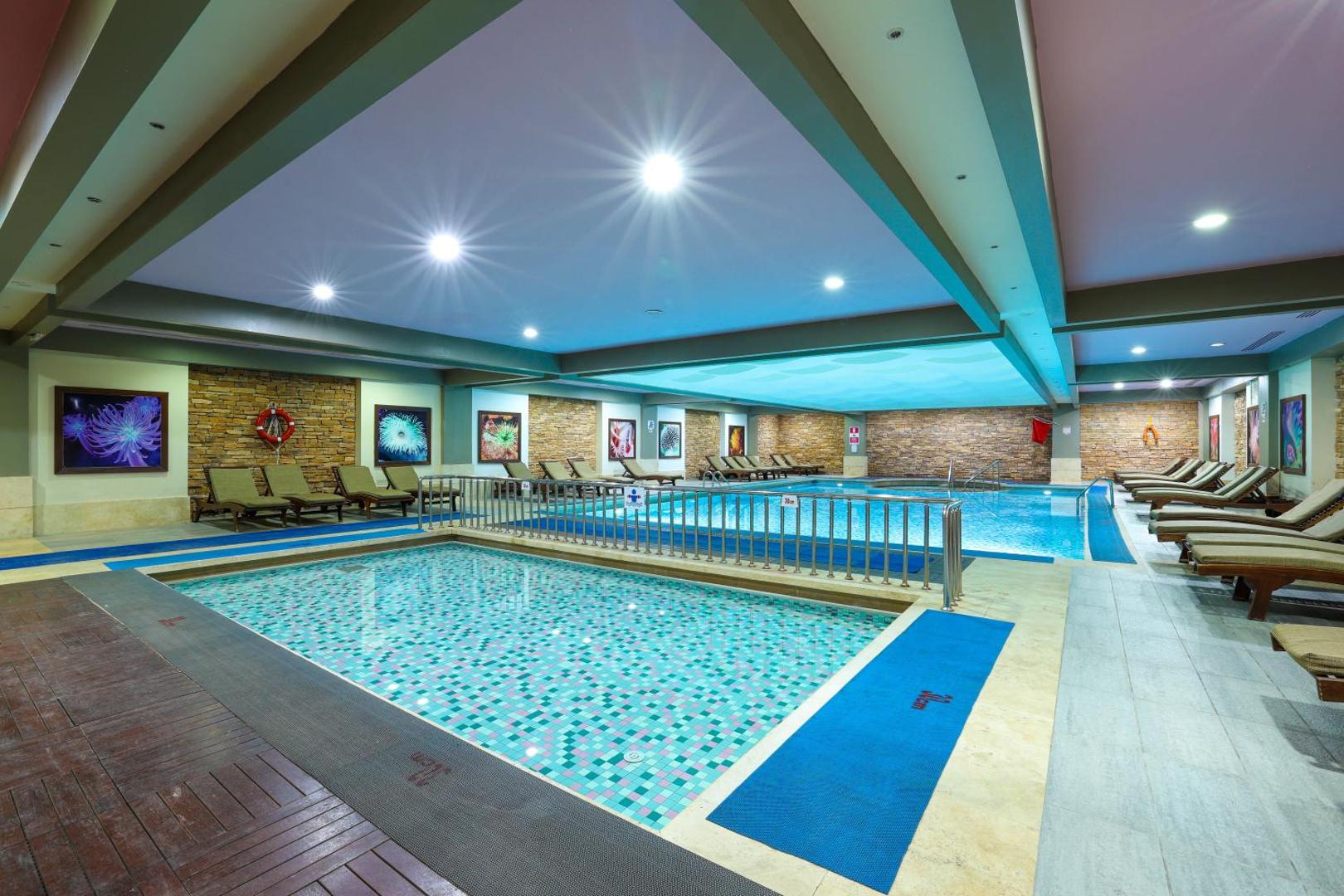 Crystal Palace Luxury Resort & Spa iekštelpu spa baseins ar atpūtas krēsliem, dekoratīvām akmens sienām un bērnu peldēšanas zonu.