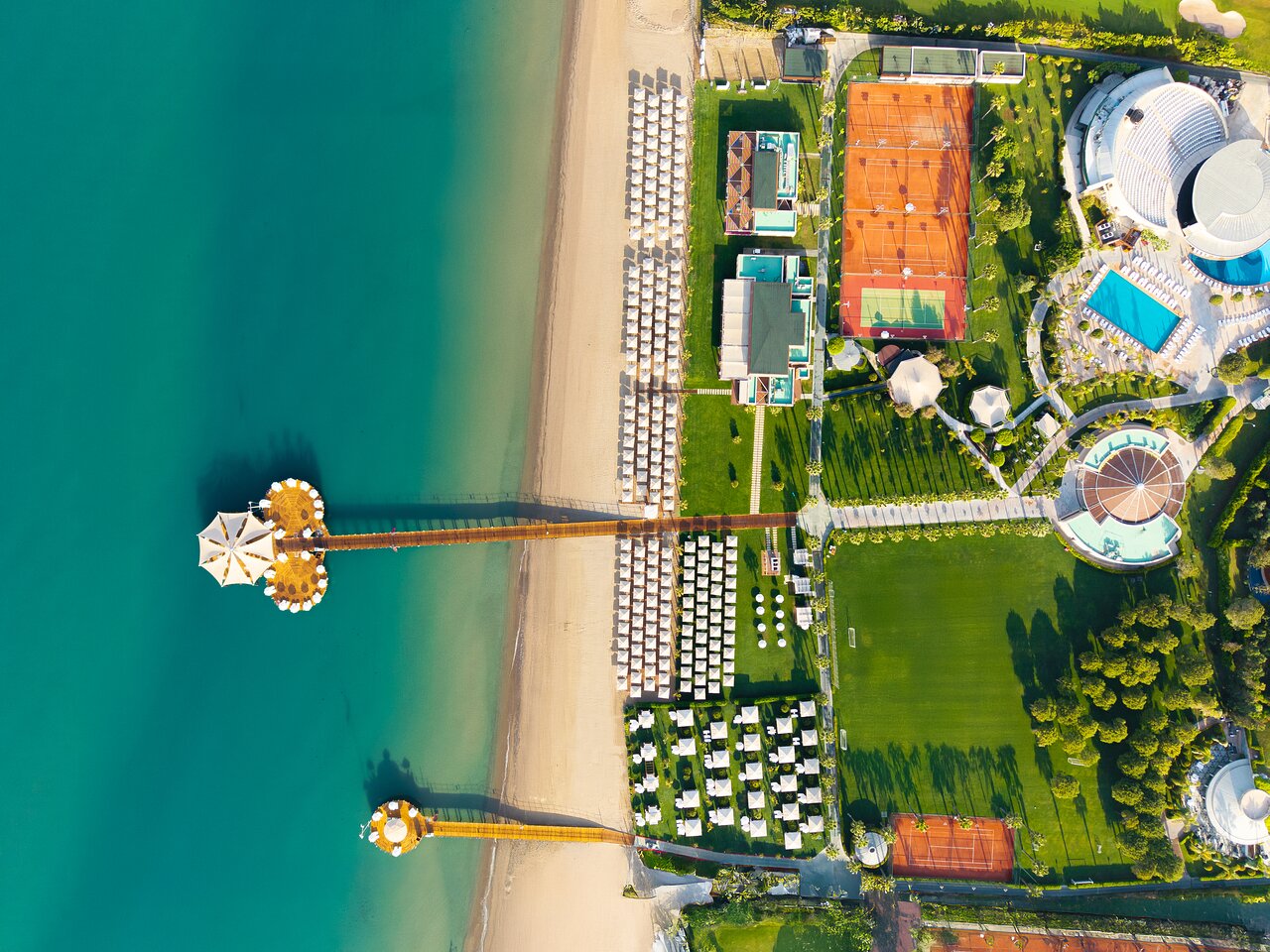 Calista Luxury Resort aerofoto uzņēmums no putna lidojuma Belekā — privātā pludmale, koka piestātnes, tenisa korti un futbola laukums pie jūras