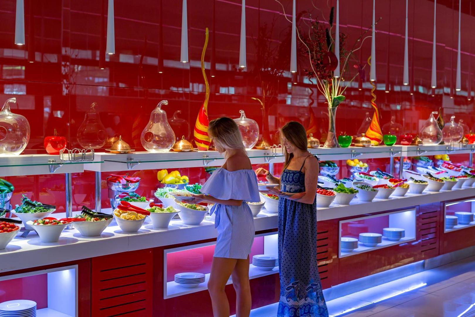 Viesnīcas Adam & Eve Hotel bufetes restorāns ar plašu svaigu salātu un dārzeņu izvēli modernā, sarkanā interjerā