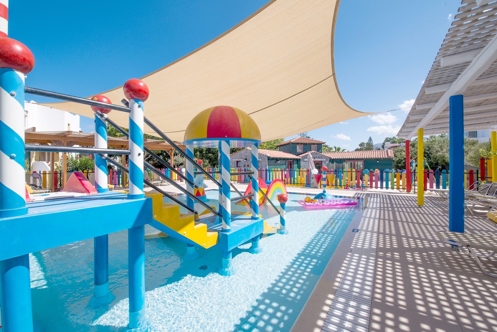 Alexander Beach Hotel & Village bērnu baseins ar maziem slidkalniņiem un saules aizsegu Malijā — droša un krāsaina rotaļu zona