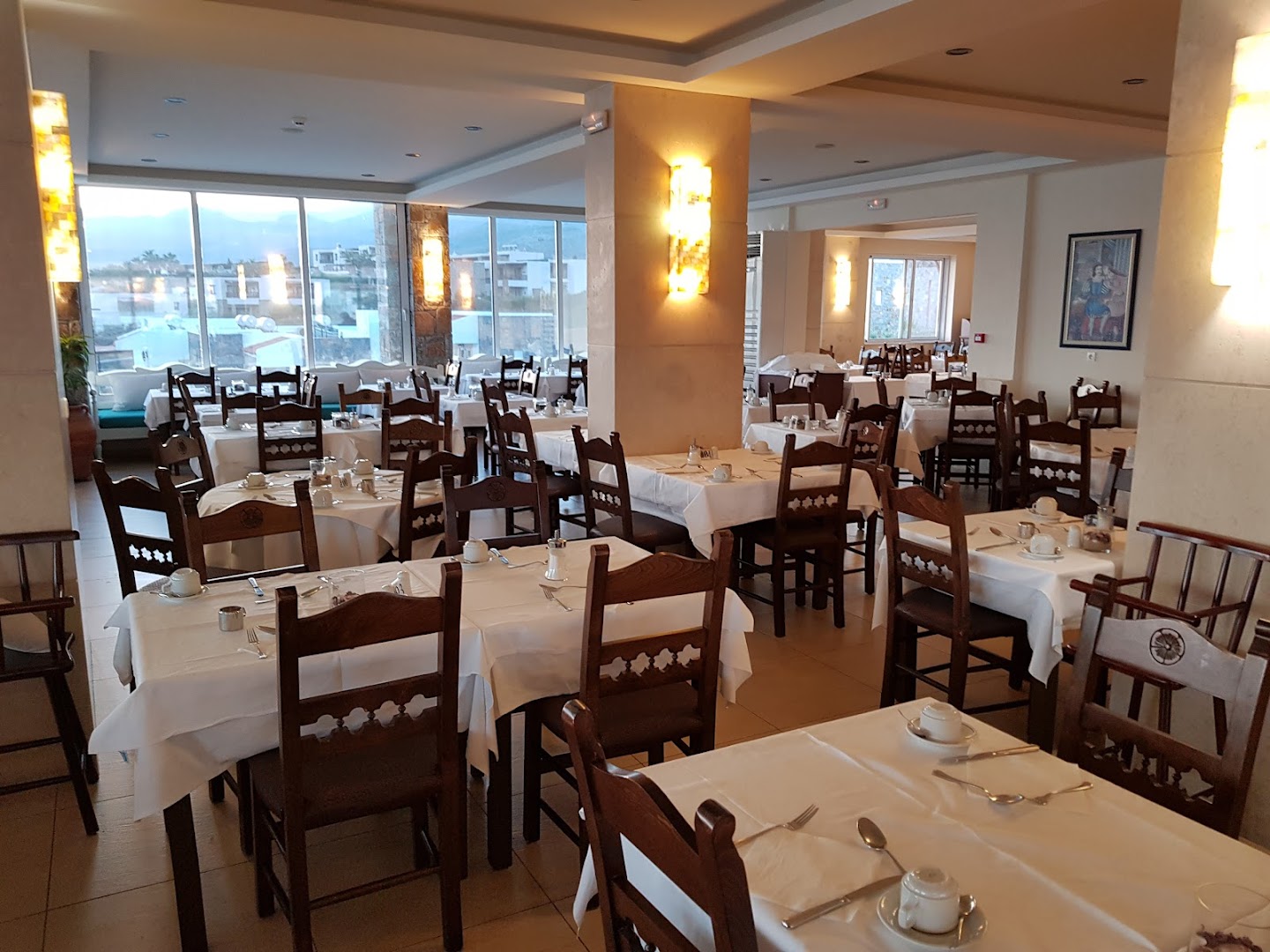 Alexander Beach Hotel & Village galvenais restorāns ar koka mēbelēm un plašiem logiem Malijā, Krētā — gaiša brokastu un vakariņu zona