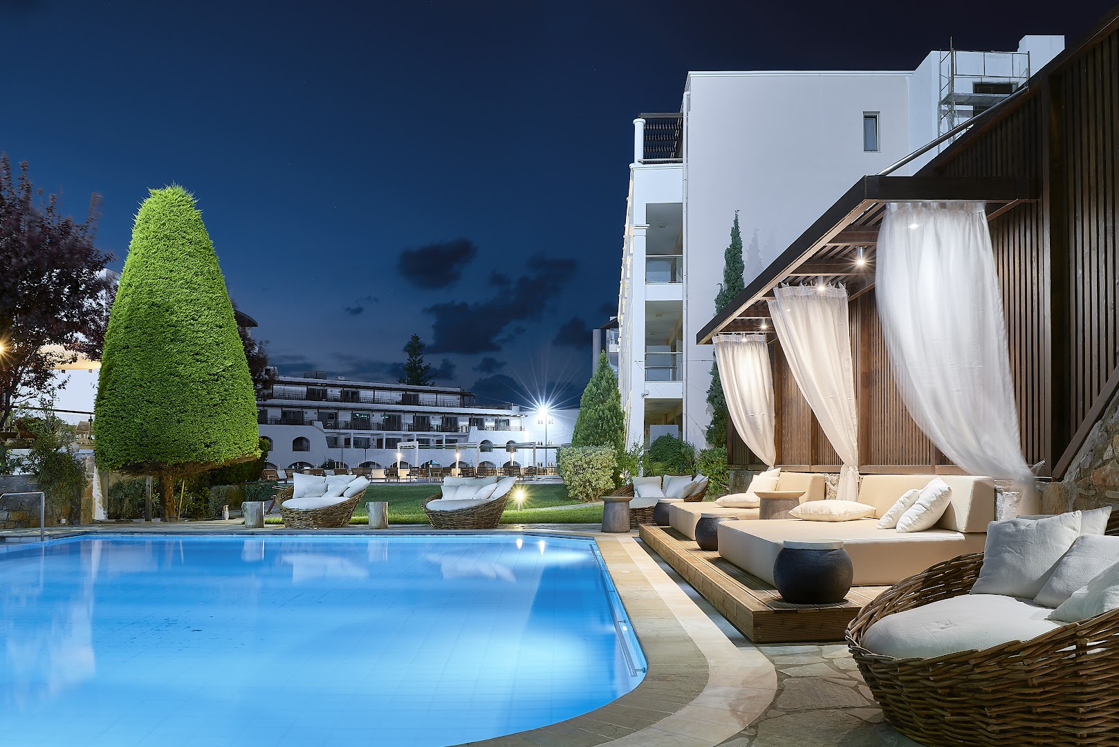 Albatros Spa & Resort baseina zona vakarā ar izgaismotām atpūtas nojumēm, pītiem krēsliem un romantisku atmosfēru