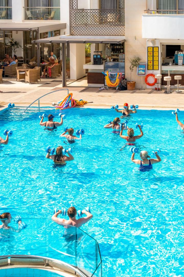 Albatros Spa & Resort āra baseins ar ūdens aerobikas nodarbību viesiem saulainā dienā Hersonisas kūrortā