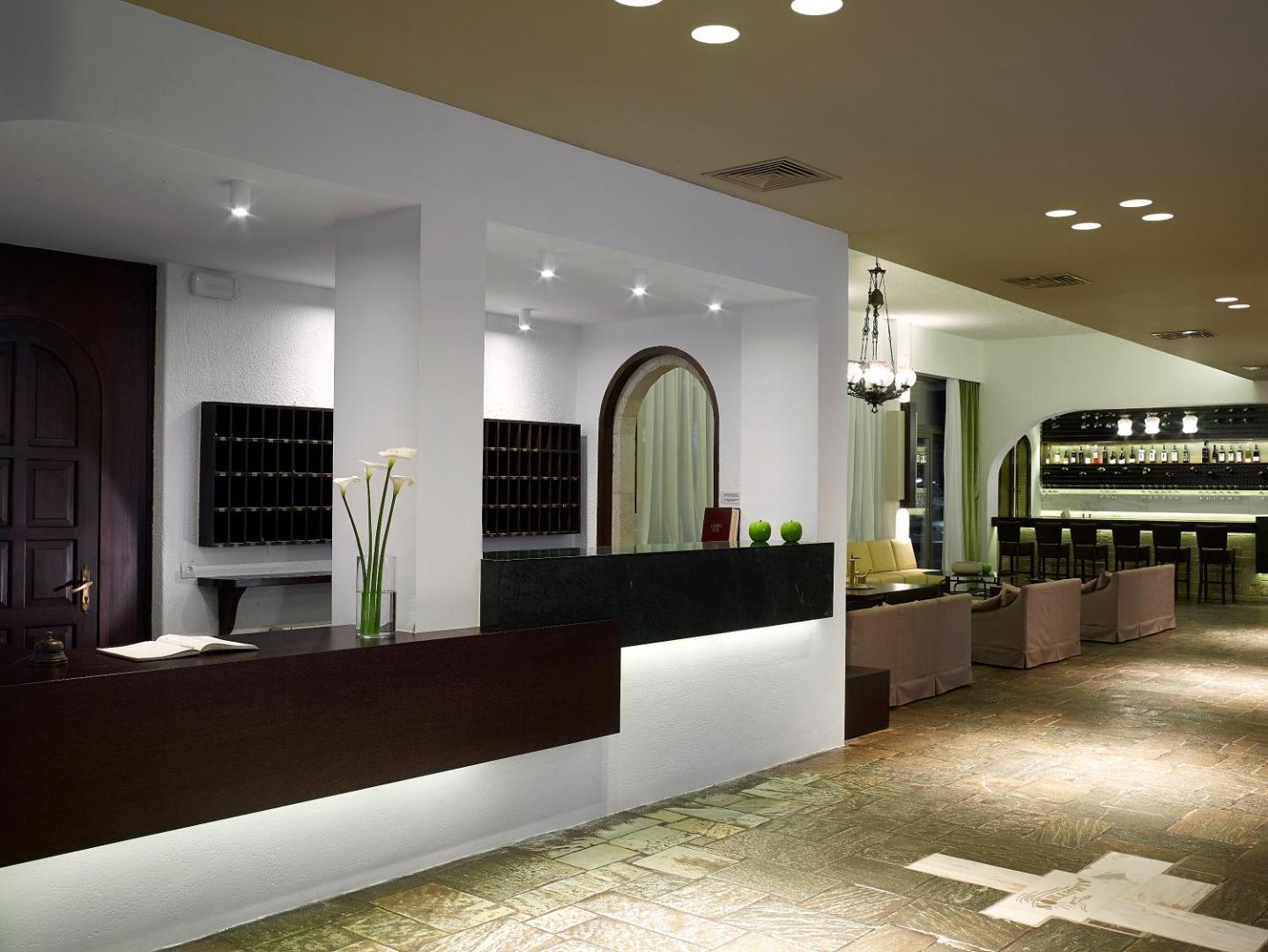 Albatros Spa & Resort viesnīcas recepcijas zona un lobby bārs ar akmens flīžu grīdu un tumša koka apdari Krētā.