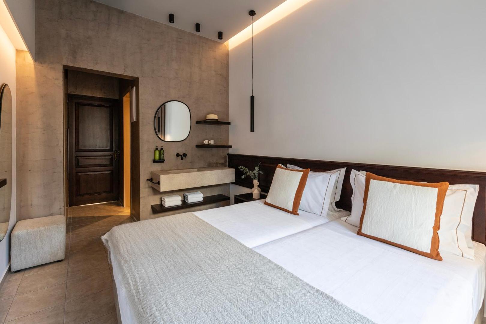 Albatros Spa & Resort numura interjers ar atvērta plānojuma izlietni, modernu spoguli un tumša koka dizaina elementiem