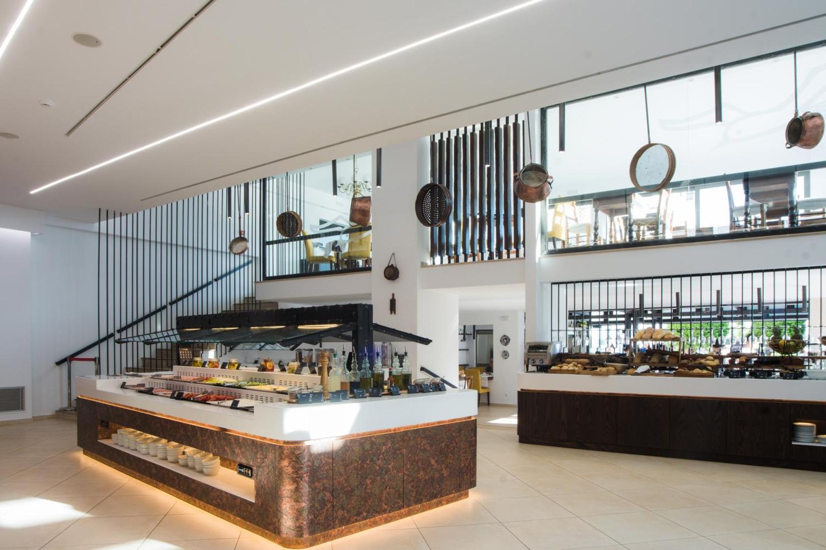 Albatros Spa & Resort viesnīcas restorāna bufetes zona ar plašu ēdienu izvēli, modernu interjeru un dekoratīviem vara traukiem pie sienām.
