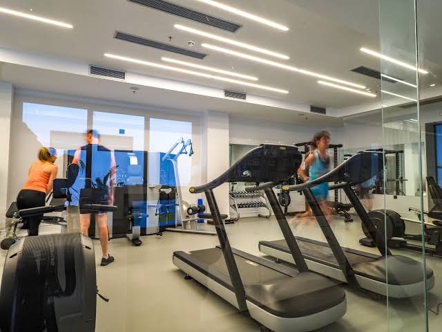 Abaton Island Resort & Spa sporta zāle ar skrejceliņiem un modernu aprīkojumu, kurā viesi sporto gaišā un plašā telpā