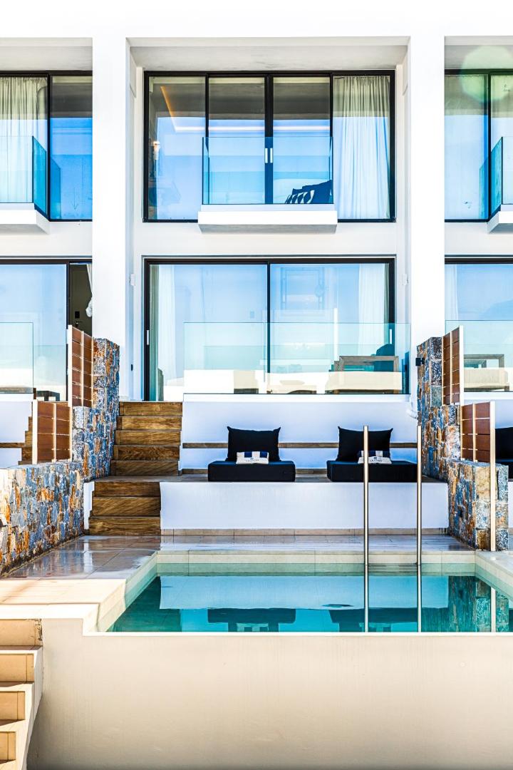 Abaton Island Resort & Spa numurs ar privātu baseinu un atpūtas zonu, akmens mūra sienas un stikla balkoni