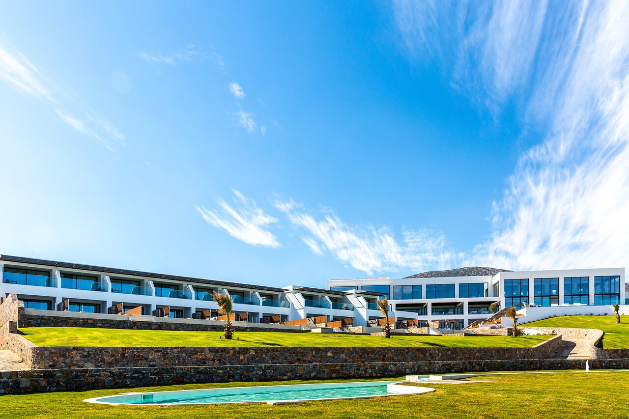 Abaton Island Resort & Spa viesnīcas modernā arhitektūra ar koptu zālienu un dekoratīvu baseinu Hersonisas reģionā