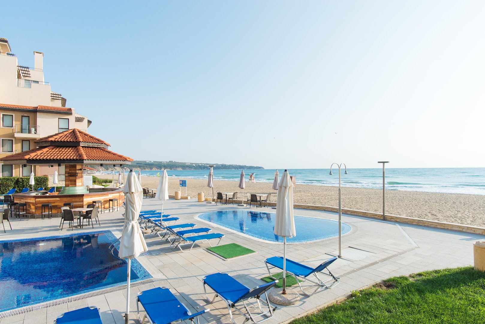 Obzor Beach Resort āra baseins un atpūtas zona pie smilšu pludmales Obzorā, Bulgārijā — sauļošanās krēsli, saulessargi un bārs pie jūras