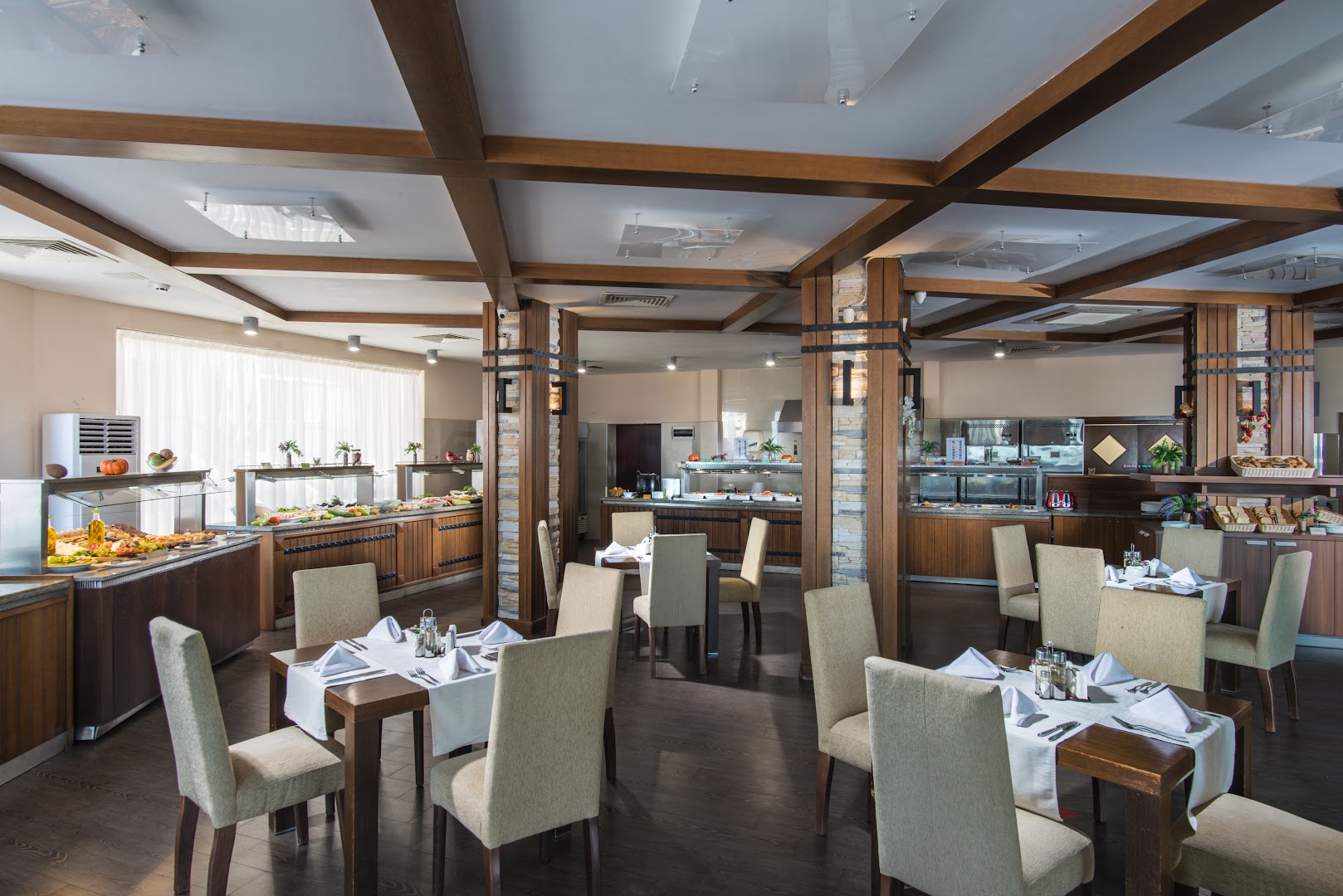 Obzor Beach Resort bufetes tipa restorāns ar plašu ēdienu izvēli, koka sijām griestos un eleganti klātiem galdiem