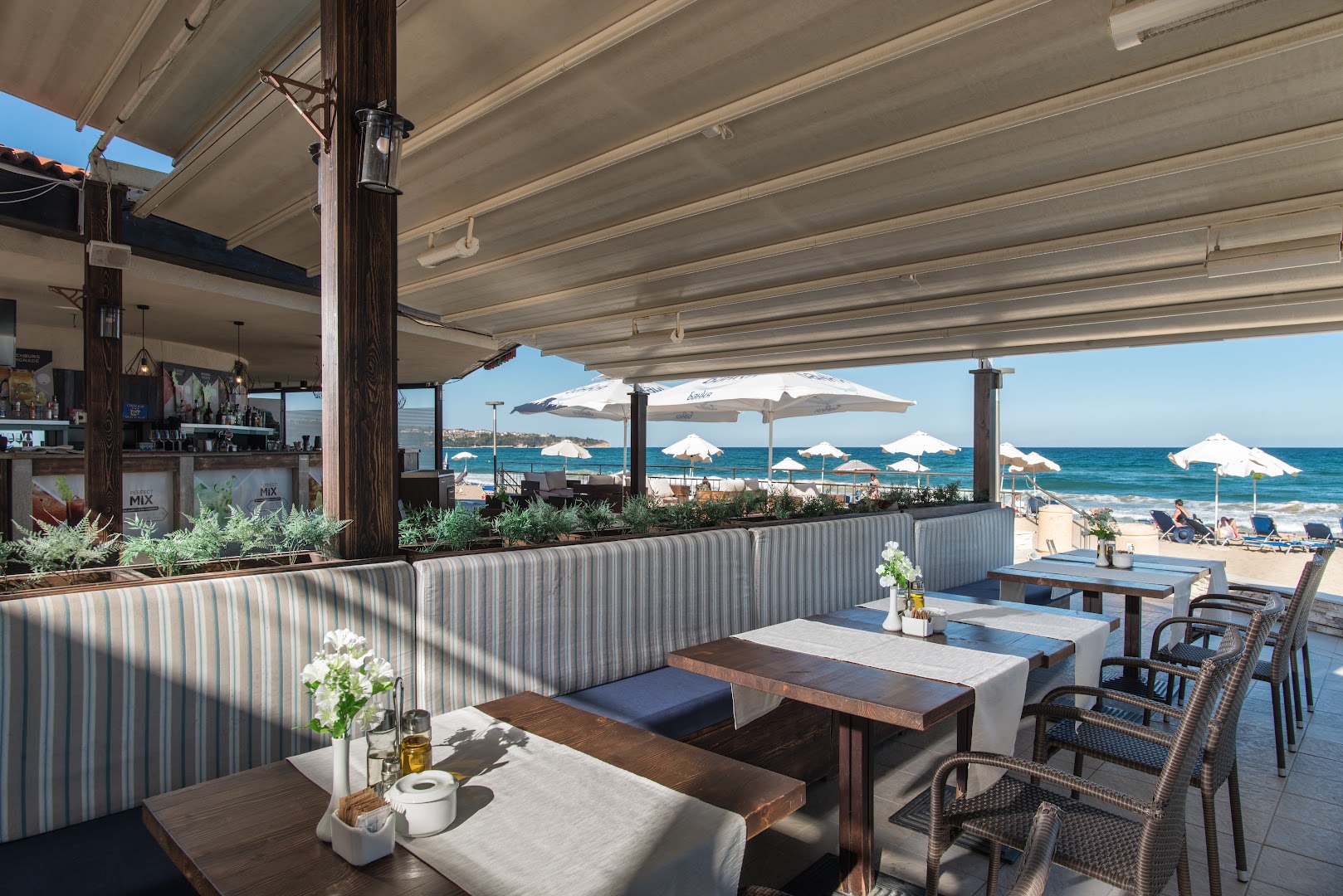 Obzor Beach Resort āra terases bārs un restorāns ar skatu uz jūru, saulessargiem un ērtām dīvāna zonām