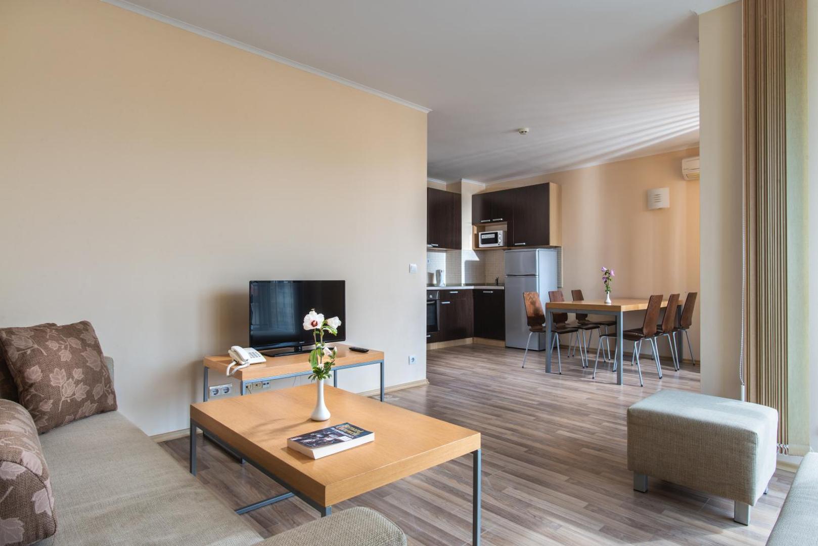 Obzor Beach Resort numura virtuves zona un dzīvojamā istaba ar TV, dīvānu un modernu koka apdari