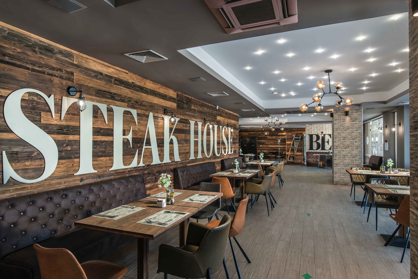 Obzor Beach Resort modernais Steak House restorāns ar koka sienu apdari, stilīgu apgaismojumu un ērtiem ādas krēsliem