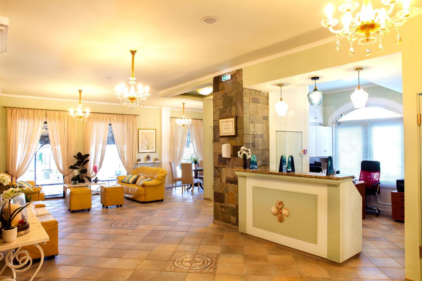 Molfetta Beach Hotel viesnīcas vestibils un recepcijas zona Korfu salā — gaišs interjers ar dzelteniem dīvāniem un klasiskām lustrām