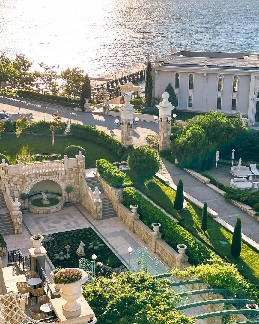 Astor Garden viesnīcas dārza arhitektūra ar akmens kāpnēm un skatu uz jūru Bulgārijas piekrastē saulrietā
