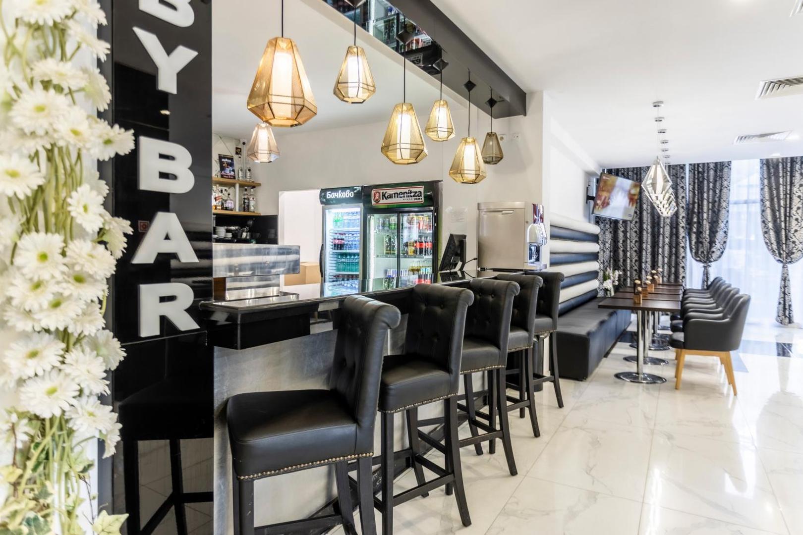 Prestige Deluxe Hotel Aquapark Club lobby bārs ar moderniem melnas ādas krēsliem, dizaina gaismekļiem un plašu dzērienu izvēli Zelta Smiltīs.