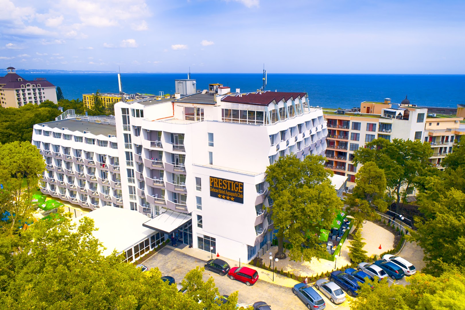 Prestige Deluxe Hotel Aquapark Club fasāde un teritorija pie jūras Zelta Smiltīs — balta daudzstāvu ēka ar balkoniem un skatu uz Melno jūru