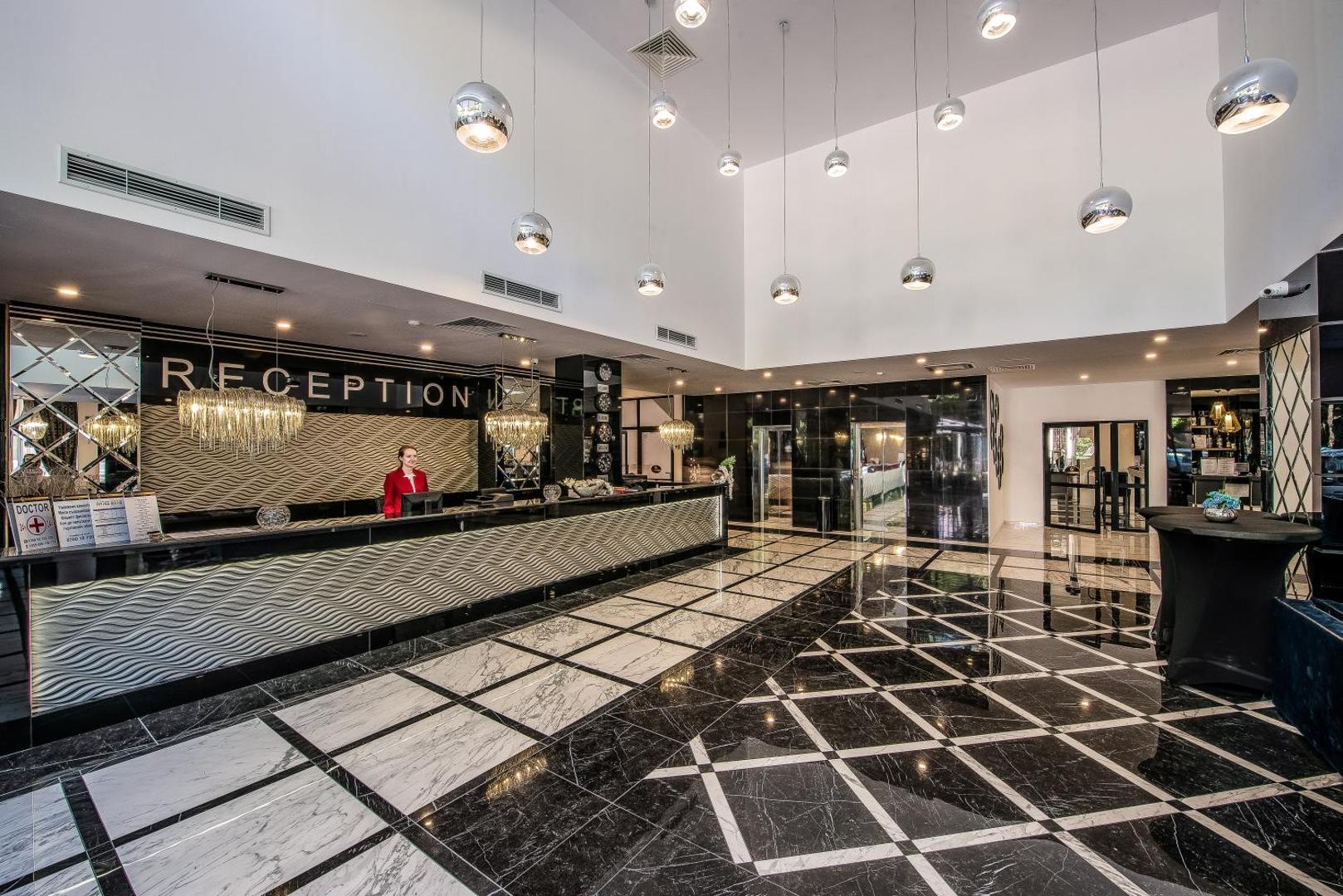 Prestige Deluxe Hotel Aquapark Club plašais vestibils ar modernu recepcijas leti, marmora grīdu un dizaina gaismekļiem