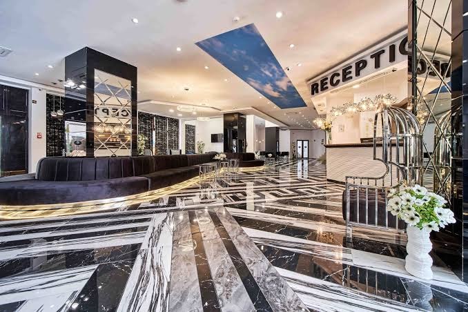 Prestige Deluxe Hotel Aquapark Club vestibila atpūtas zona ar mīkstajiem dīvāniem, spoguļsienām un greznu marmora grīdas rakstu