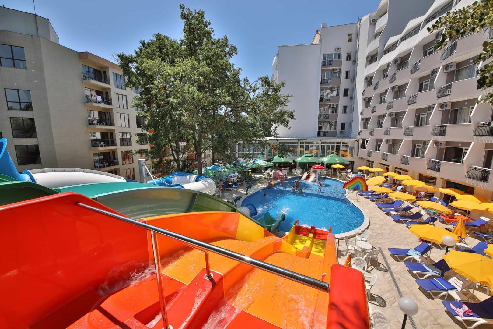 Prestige Deluxe Hotel Aquapark Club viesnīcas ēka un akvaparka zona ar baseinu, saulessargiem un slidkalniņiem Zelta Smiltīs