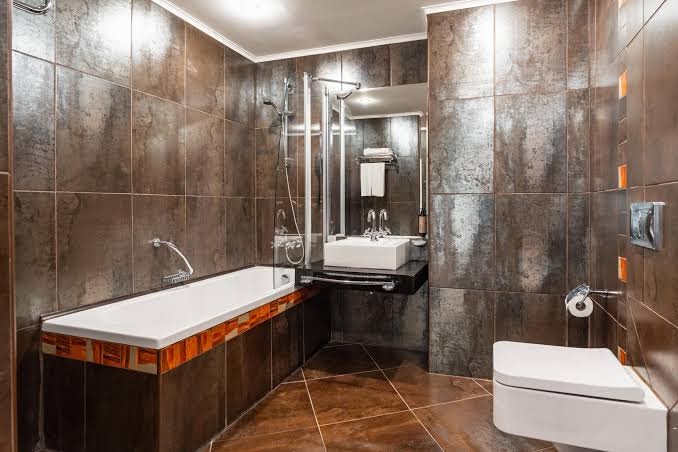 Moderna Festa Via Pontica Resort numura vannas istaba ar tumšām flīzēm, vannu, izlietni un lielu spoguli