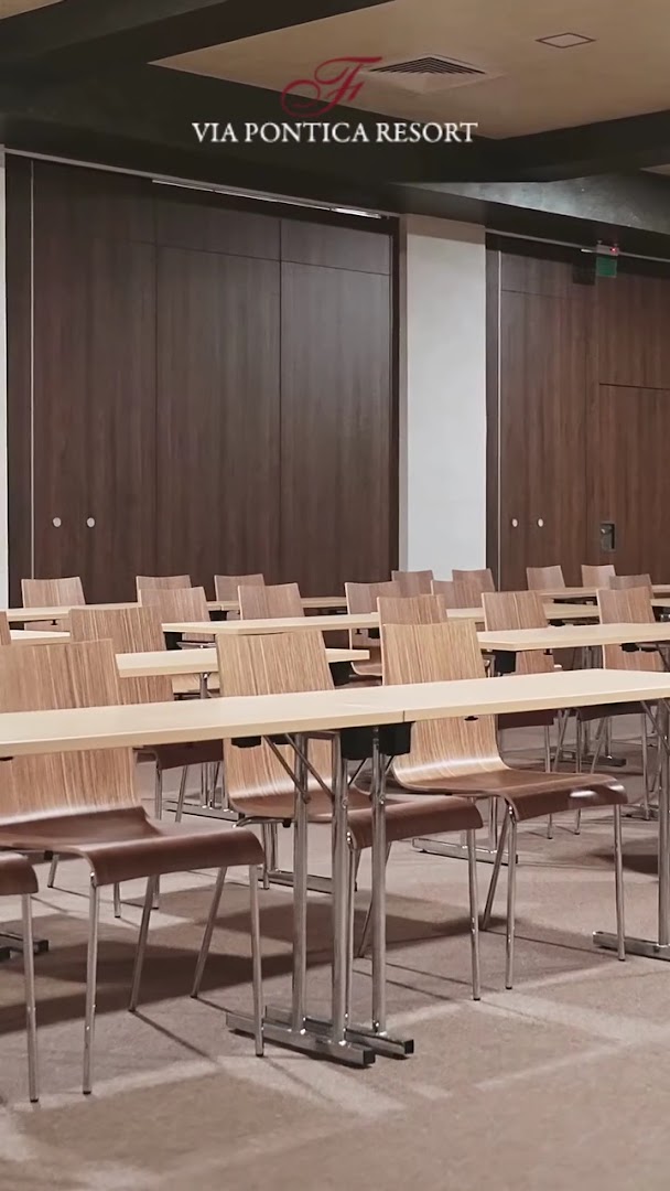 Festa Via Pontica Resort konferenču zāle ar koka krēsliem un galdiem, piemērota semināriem un biznesa pasākumiem