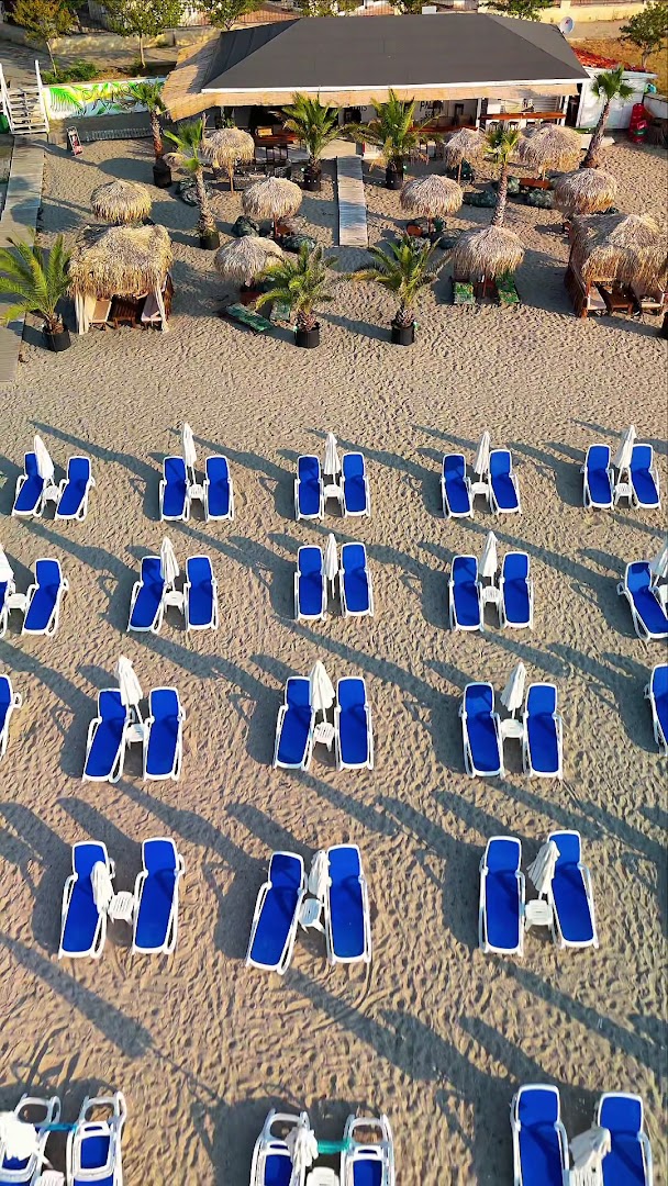 Festa Via Pontica Resort pludmales zona ar ziliem sauļošanās krēsliem, saulessargiem un bāru zem salmu jumtiem Pomorijā, Bulgārijā