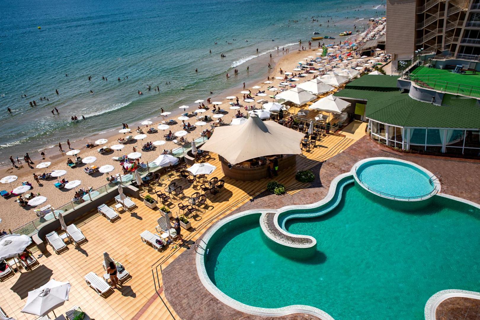 MPM Hotel Arsena skats no augšas uz āra baseinu, saulaino terasi un blakus esošo smilšu pludmali Nesebārā, Bulgārijā