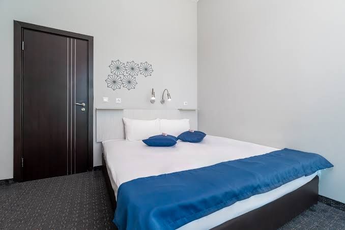 MPM Hotel Arsena moderna guļamistaba ar tumša koka durvīm un dekoratīviem elementiem pie sienas — mājīgs numurs atpūtai