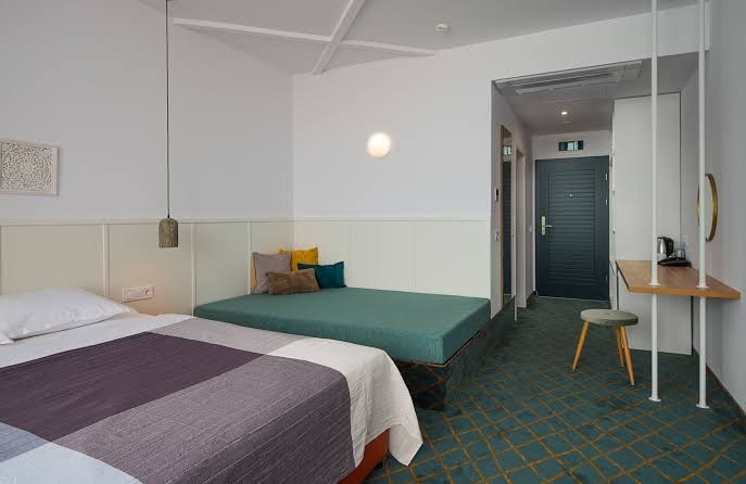 Viesnīcas Sunrise Blue Magic Resort numura interjers ar papildu gultu mazuļiem vai bērniem un nelielu darba zonu