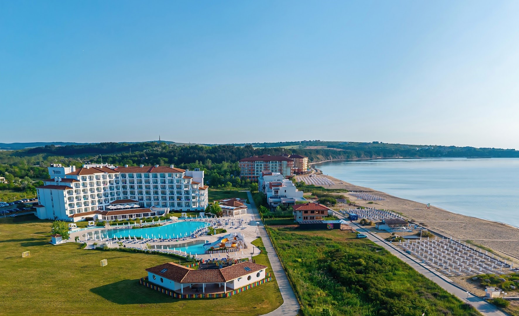 Sunrise Blue Magic Resort panorāmas skats no putna lidojuma Obzorā, Bulgārijā — viesnīcas ēka, baseinu zona un plaša smilšu pludmale pie Melnās jūras