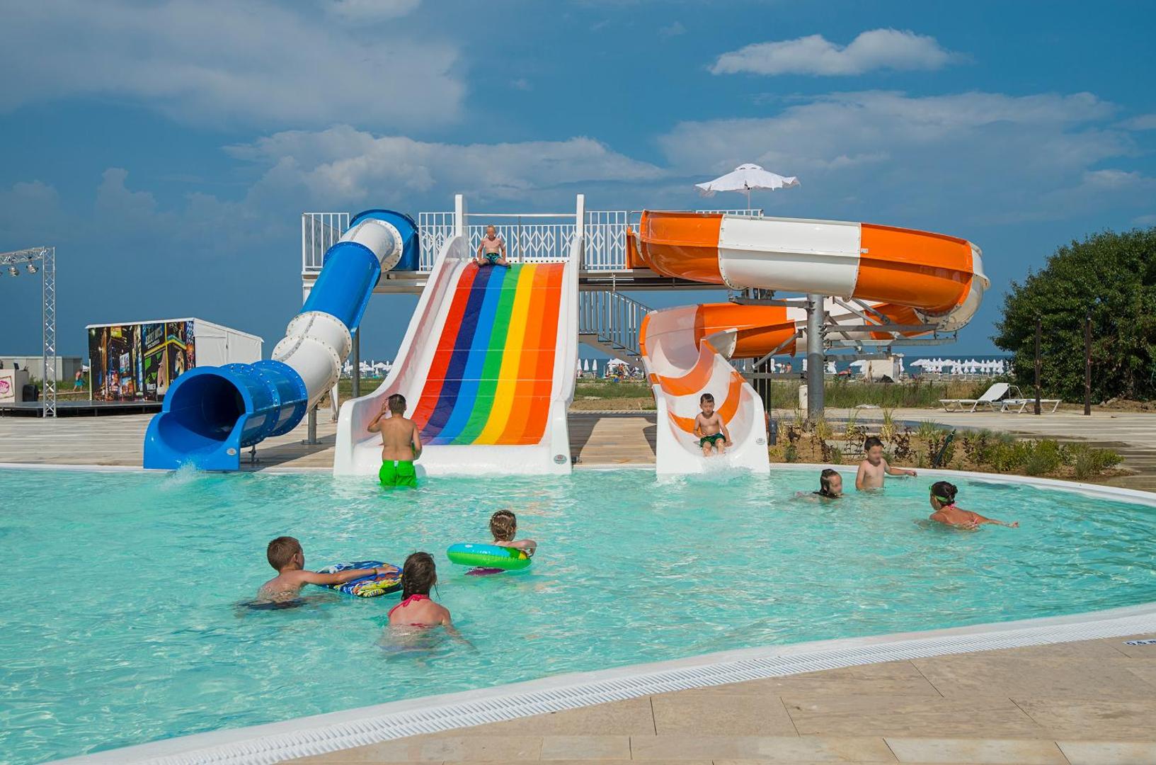 Bērnu baseins ar krāsainiem ūdens slidkalniņiem Sunrise Blue Magic Resort viesnīcā — bērni spēlējas un šļakstās ūdenī