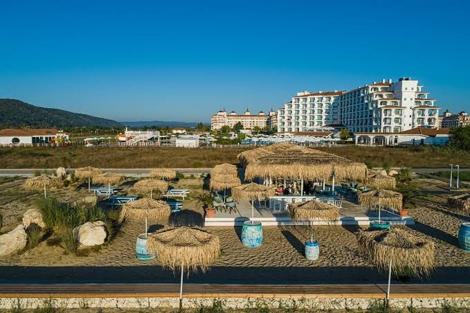Sunrise Blue Magic Resort viesnīcas ēka un pludmales klubs ar saulessargiem — skats uz moderno arhitektūru un piekrastes zonu