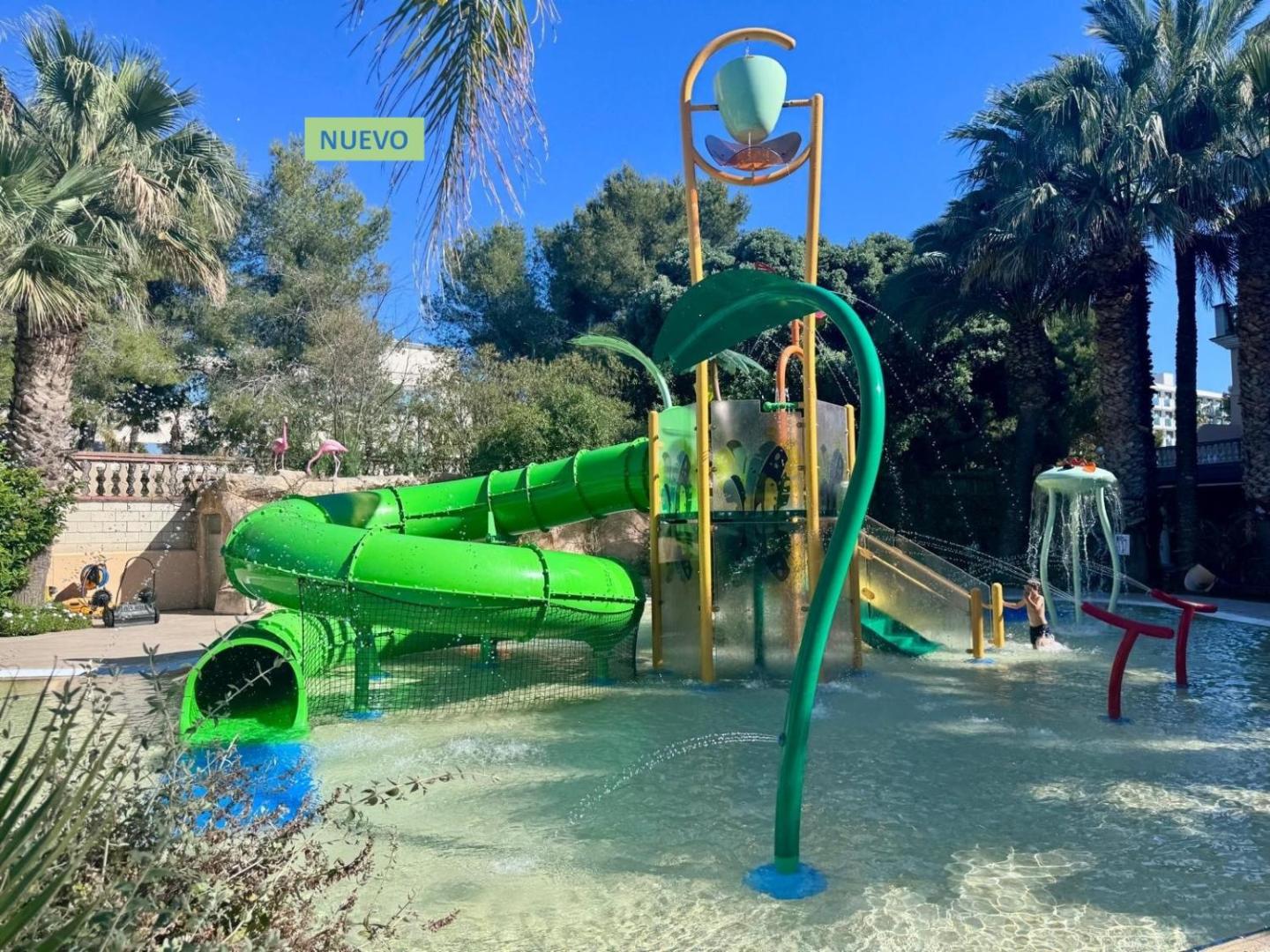 Palas Pineda viesnīcas bērnu ūdens atrakciju parks ar zaļu spirālveida slidkalniņu un ūdens strūklām palmu ieskautā teritorijā Kostadoradā.