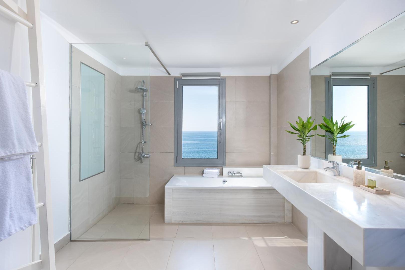 Mare Dei Ionian Resort gaiša vannas istaba ar dušu, vannu un skatu uz Jonijas jūru Peloponēsas piekrastē, Grieķijā.