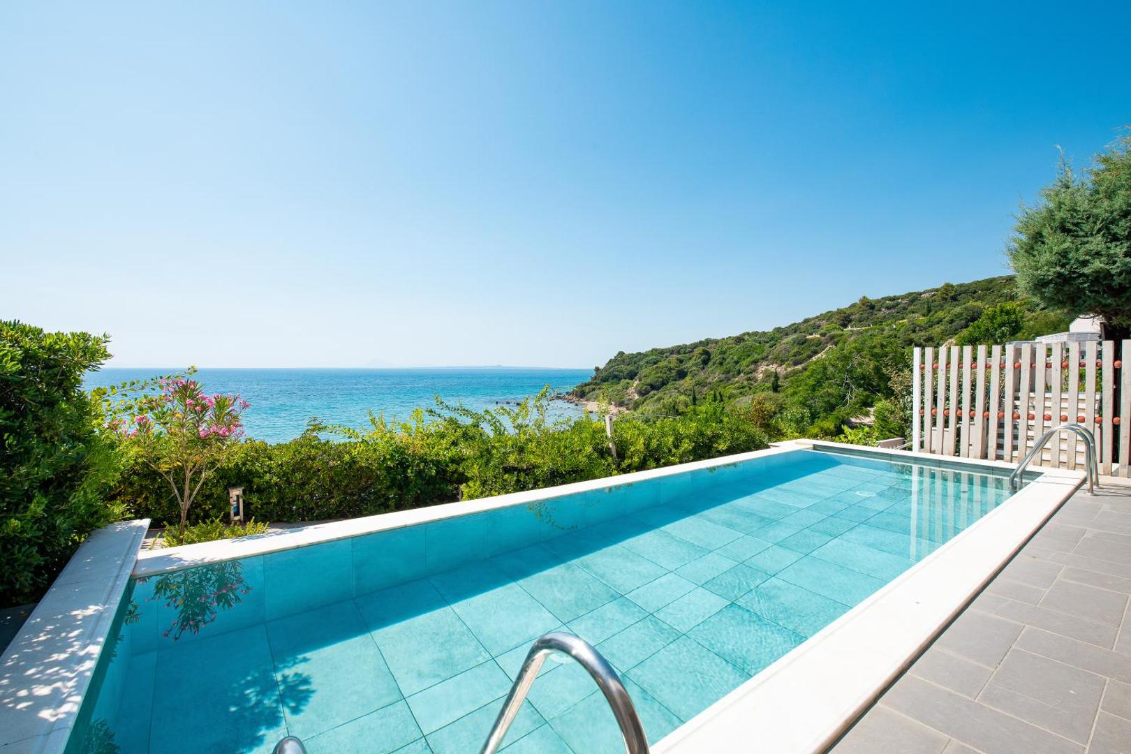 Mare Dei Ionian Resort āra baseins ar zilu flīžu apdari un skatu uz piekrastes kalniem un jūru