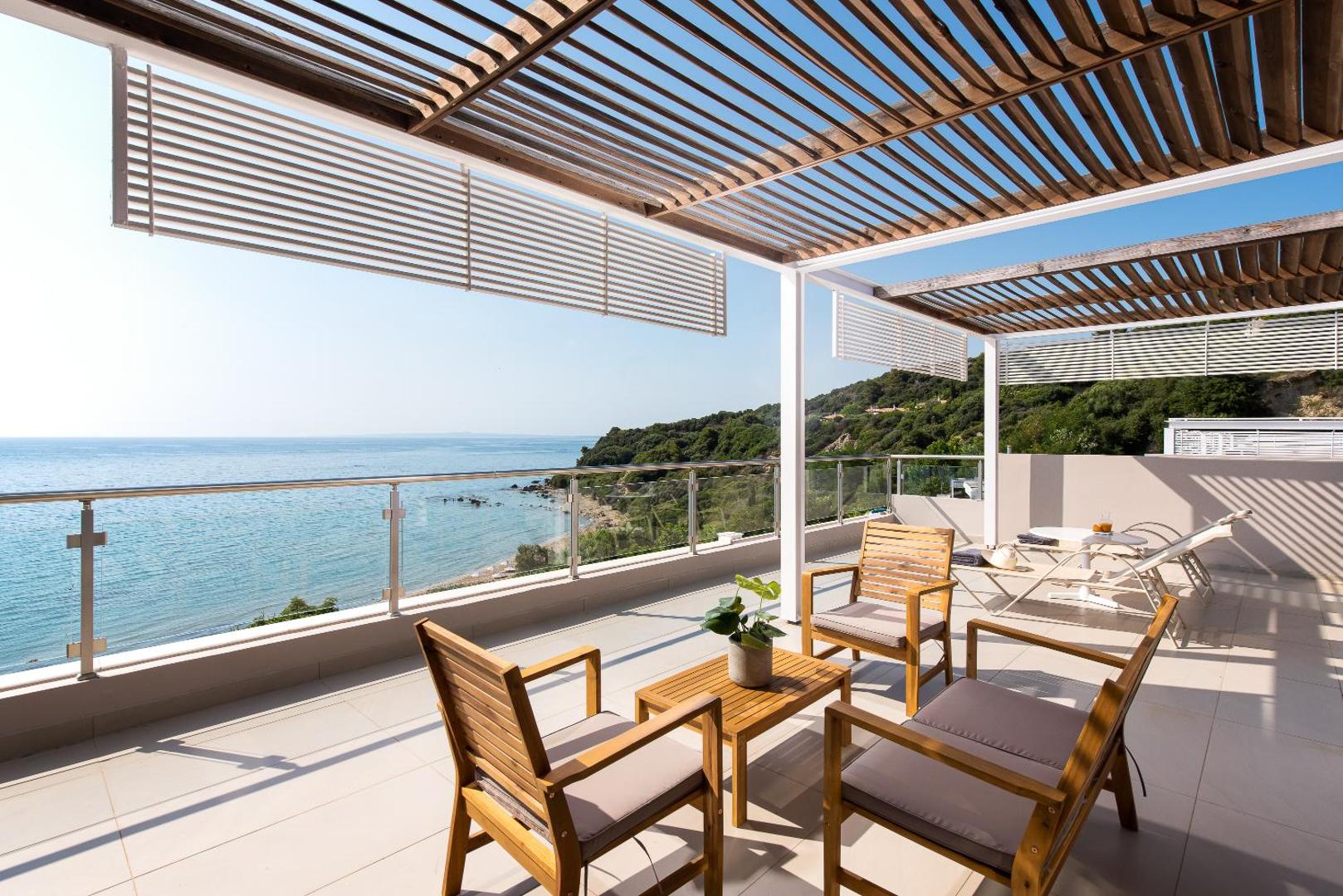 Mare Dei Ionian Resort plaša terase ar koka mēbelēm un panorāmas skatu uz piekrasti un Jonijas jūru