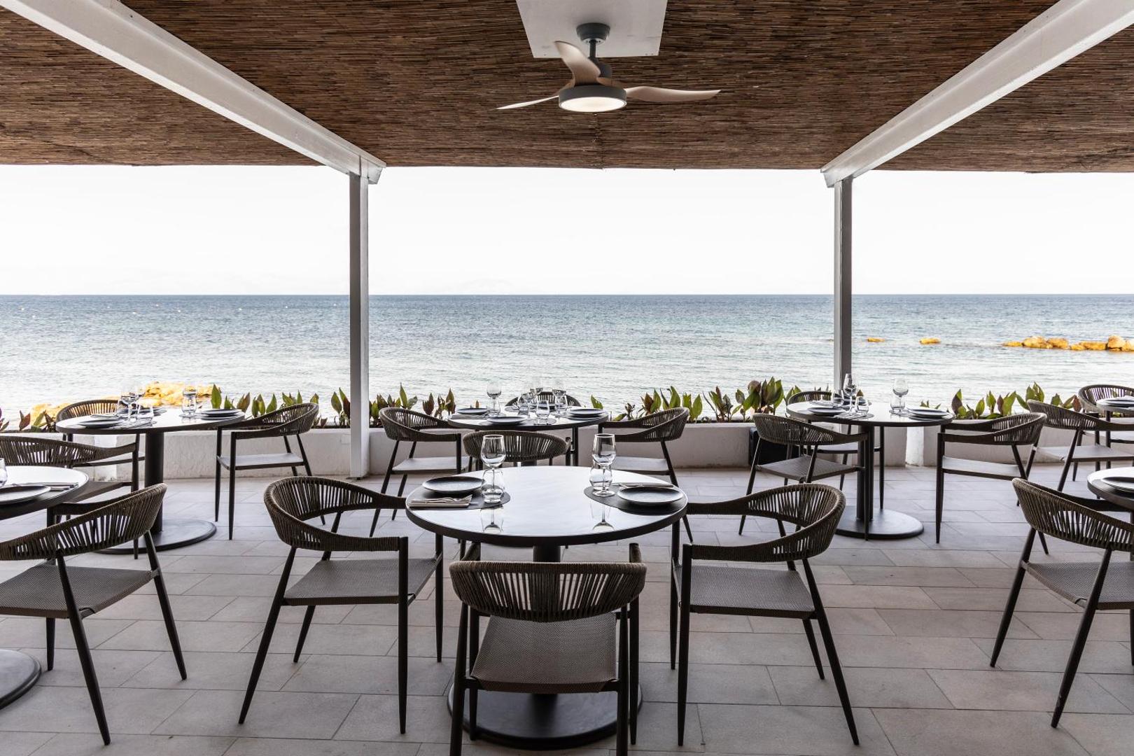 Valmar Corfu restorāna āra terase ar modernām mēbelēm un skatu uz jūru, nodrošinot patīkamu atmosfēru maltītēm piekrastē