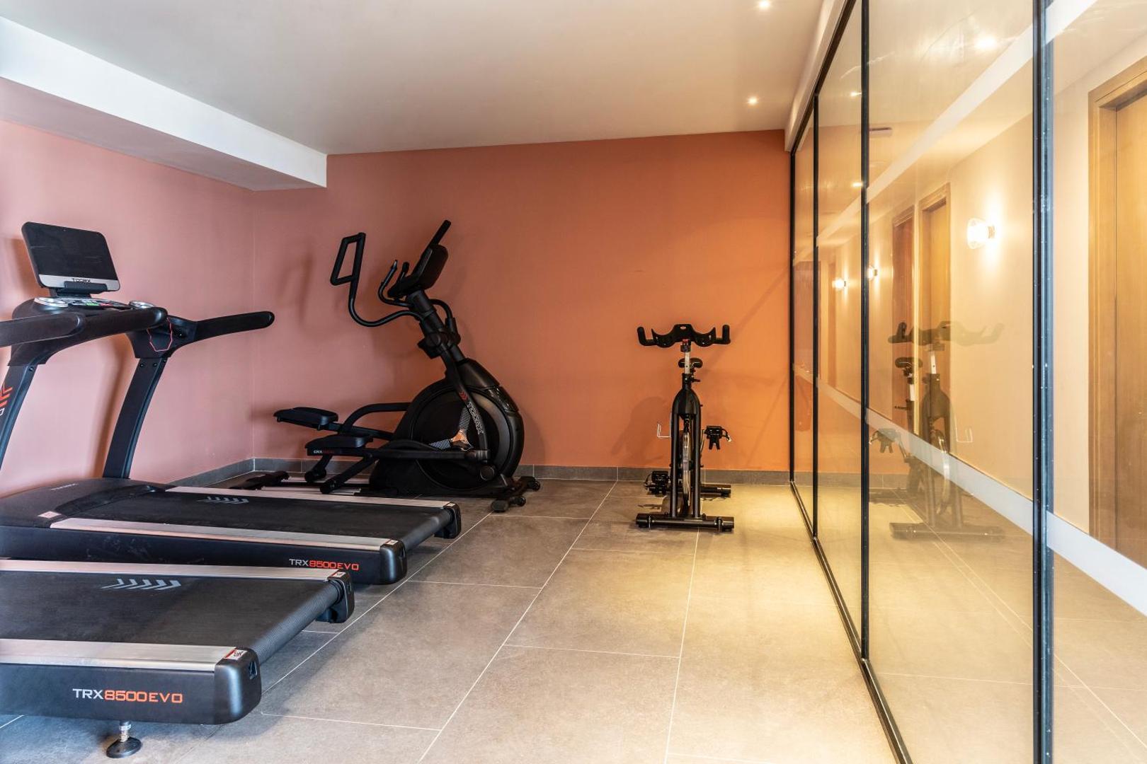 Valmar Corfu fitnesa zāle ar moderniem TRX skrejceļiem un velotrenažieriem — gaišas telpas ar spoguļsienu sporta nodarbībām