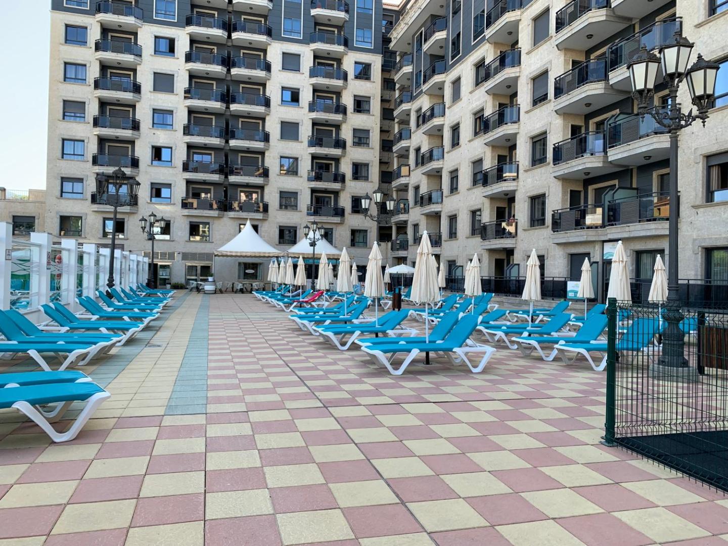 Apartamentos Nuria Sol sauļošanās terase ar ziliem zviļņiem un saulessargiem pie viesnīcas ēkas Fuengirolā