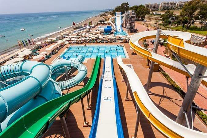 Eftalia Ocean akvaparks pie pašas jūras — lieli ūdens slidkalniņi, baseins un skats uz smilšu pludmali un Vidusjūru