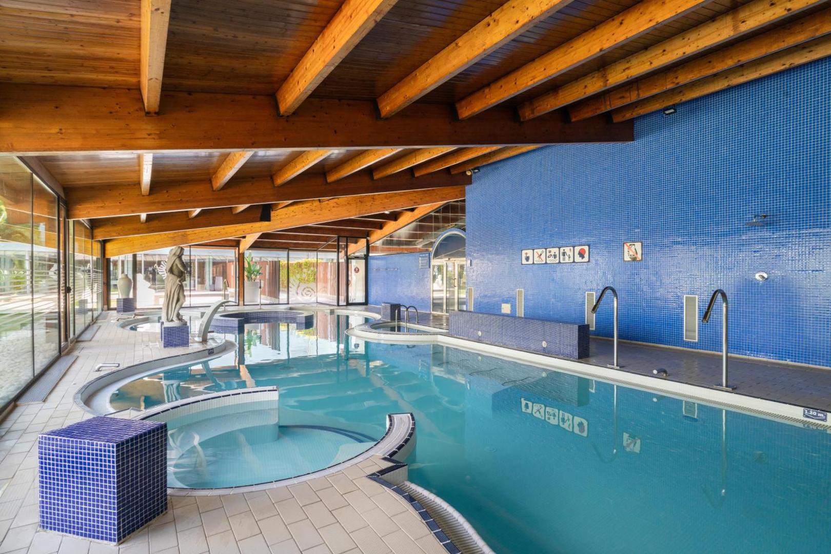 Estival Park Silmar spa centrs ar siltu iekštelpu baseinu, koka siju griestiem un zilu mozaīkas sienu Salovā