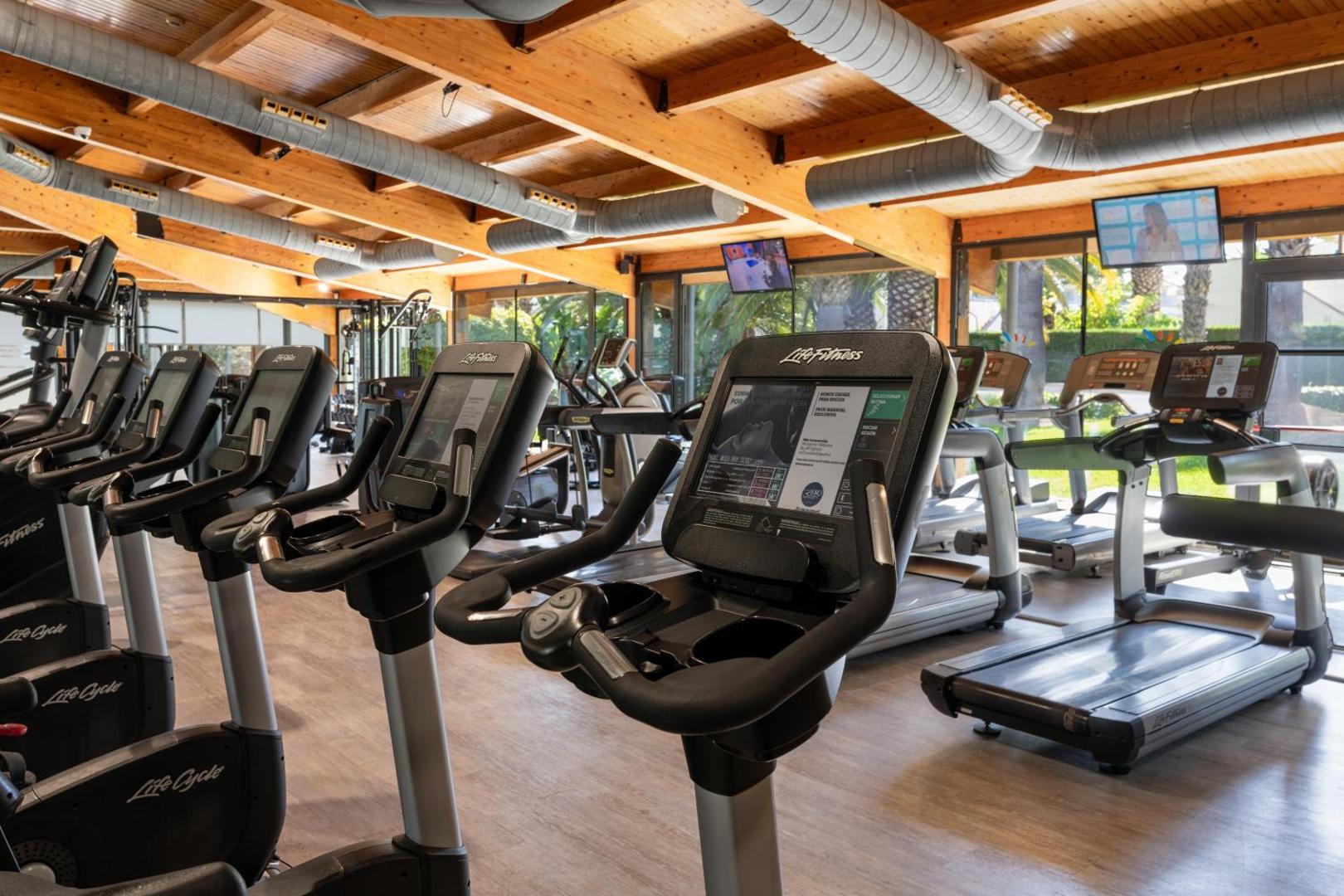Estival Park Silmar viesnīcas fitnesa centrs ar moderniem Life Fitness kardio trenažieriem un skatu uz dārzu Salovā, Spānijā