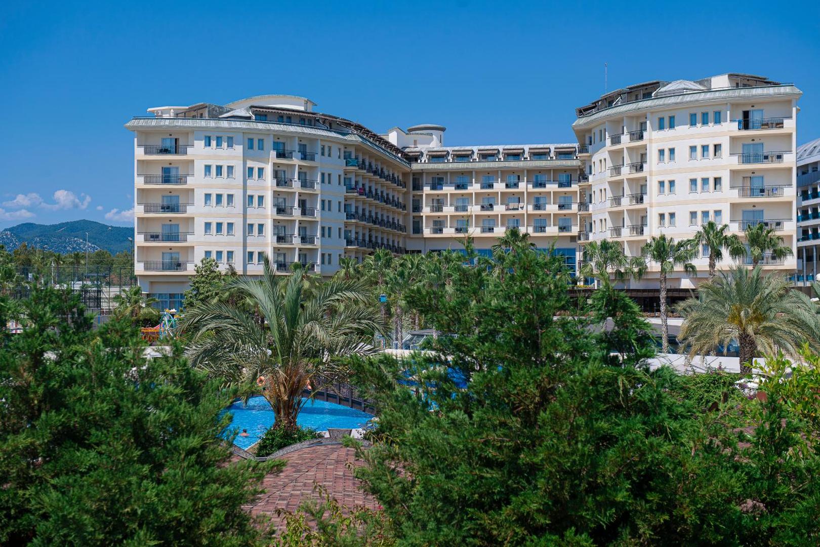Mukarnas Spa & Resort viesnīcas korpuss ar balkoniem un skatu uz dārzu un baseinu zonu saulainā dienā