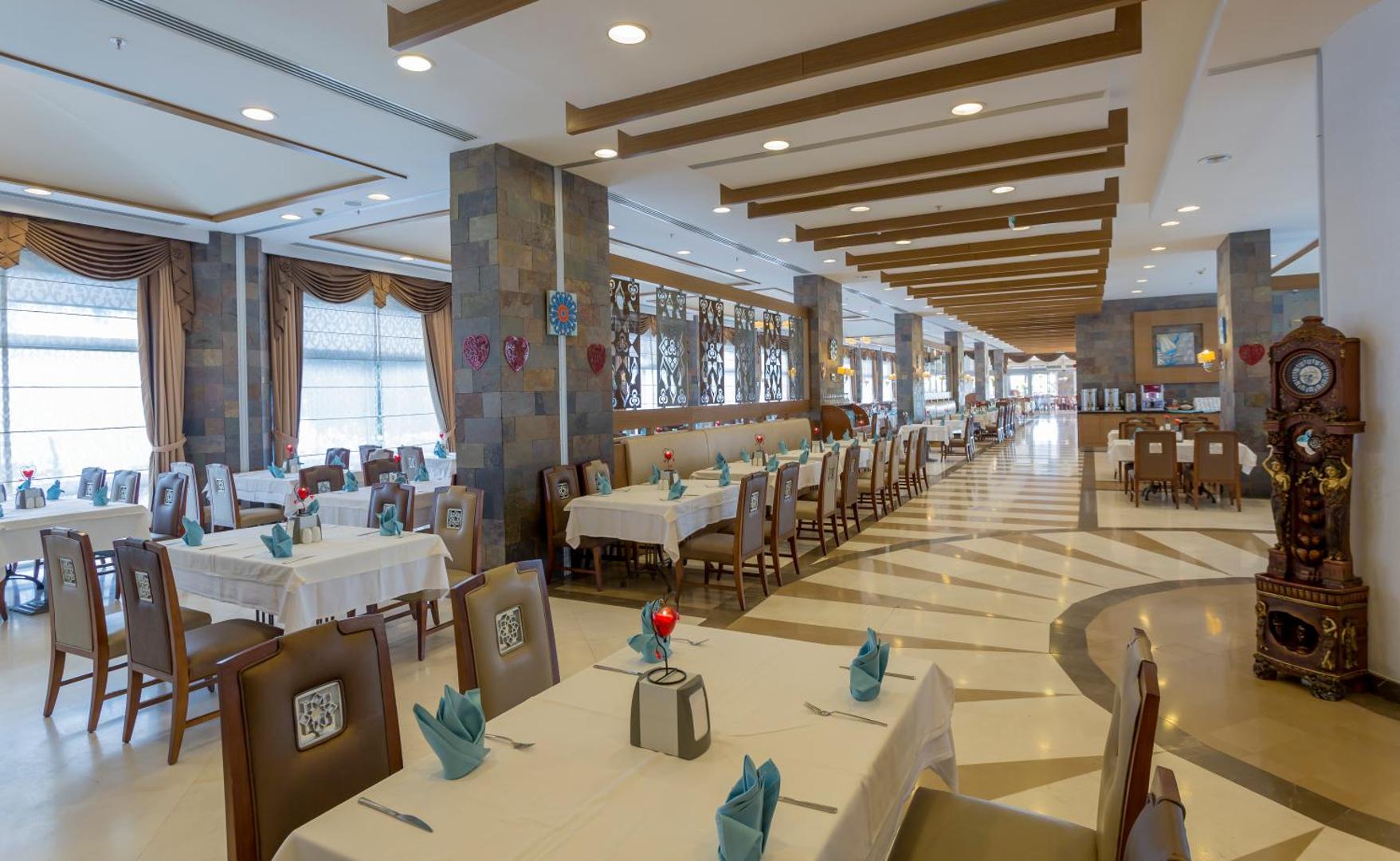 Mukarnas Spa & Resort galvenā restorāna interjers ar eleganti klātiem galdiem, akmens kolonnām un dekoratīviem griestu elementiem