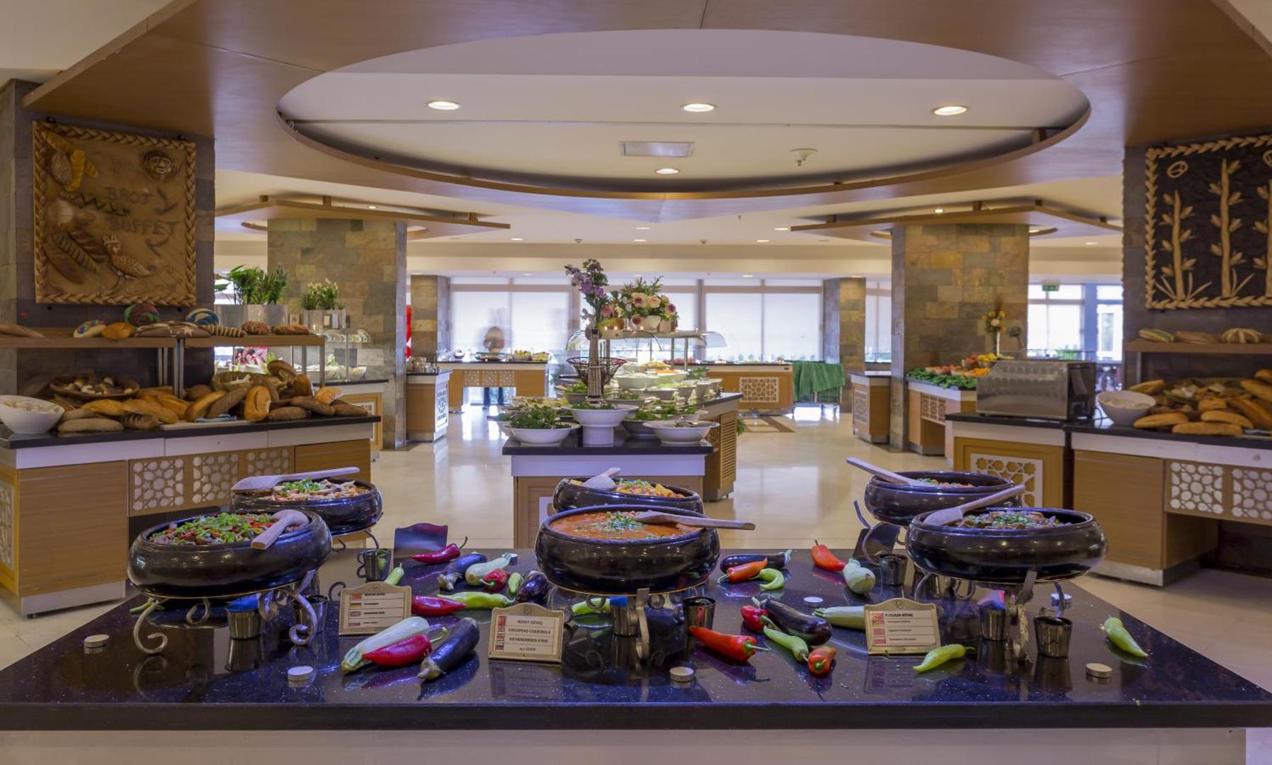 Mukarnas Spa & Resort galvenā restorāna bufetes zona ar plašu silto ēdienu, dārzeņu un svaigas maizes izvēli