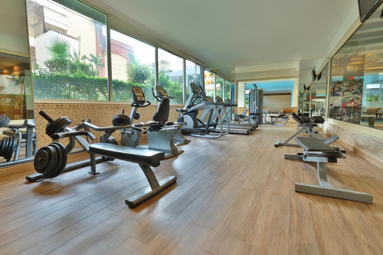 Crystal Aura Beach Resort & Spa fitnesa centrs ar moderniem trenažieriem, skrejceliņiem un panorāmas logiem uz dārzu