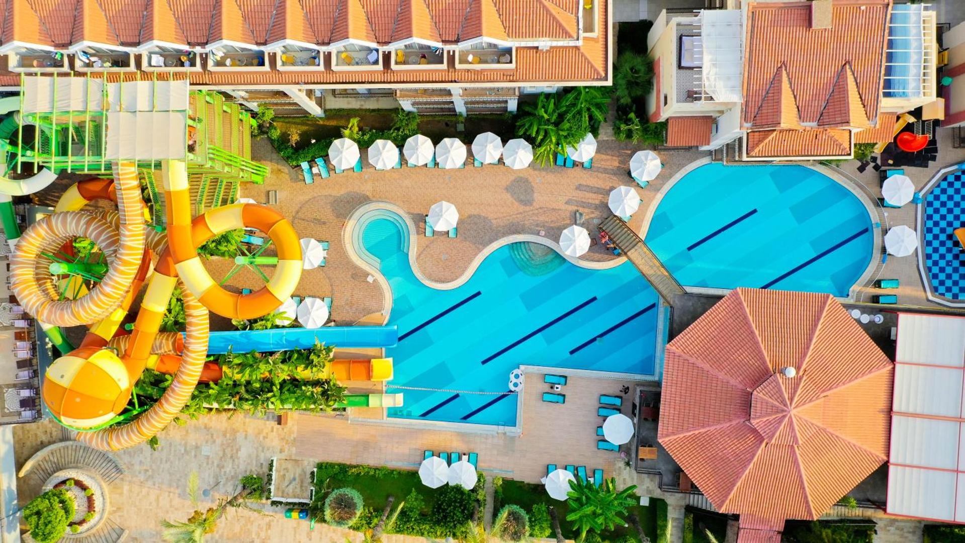 Crystal Aura Beach Resort & Spa akvaparka zona ar lielajiem ūdens slidkalniņiem un atpūtas krēsliem pie baseina no augšas